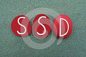 SSD, Shared Delusional Disorder, logo type composed with red colored stone letters over green sand photo